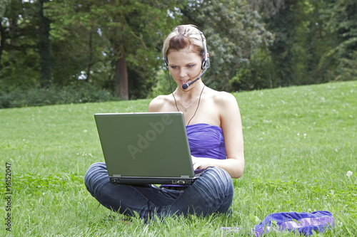 Junge Frau telefoniert über Notebook im Park