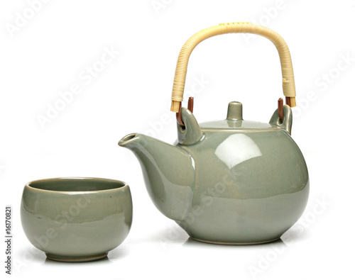 Ceramic teapot and a tea cup over white background photo