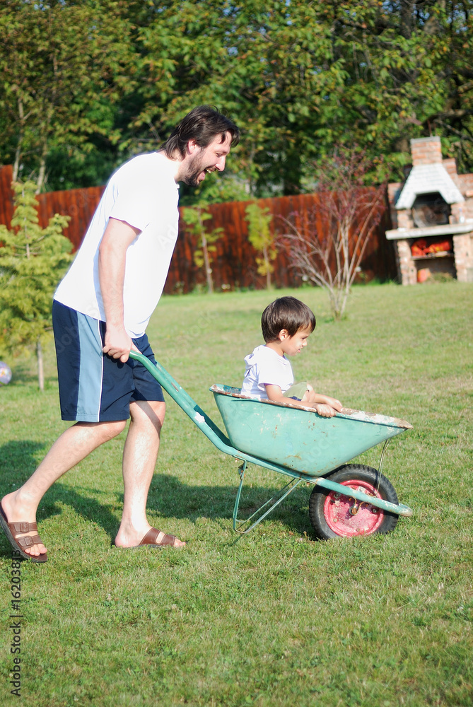 Father is playing with kid driving him on green meadow Father is playing with kid driving him on green meadow