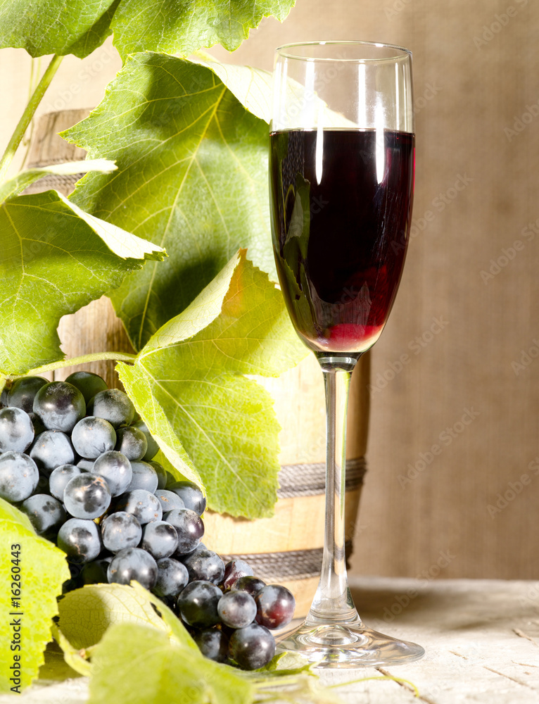 Old red wine in glass with vine and grape