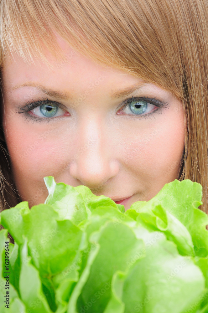 Closeup of a woman with lettuce in front of her face Closeup of a woman with lettuce in front of her face