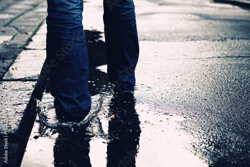 Person is walking in the streets and through a puddle