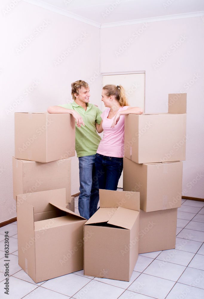 joyful couple standing in between unopened boxes joyful couple standing in between unopened boxes