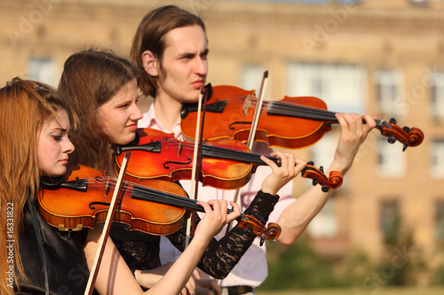 trio of violinists plays outdoor