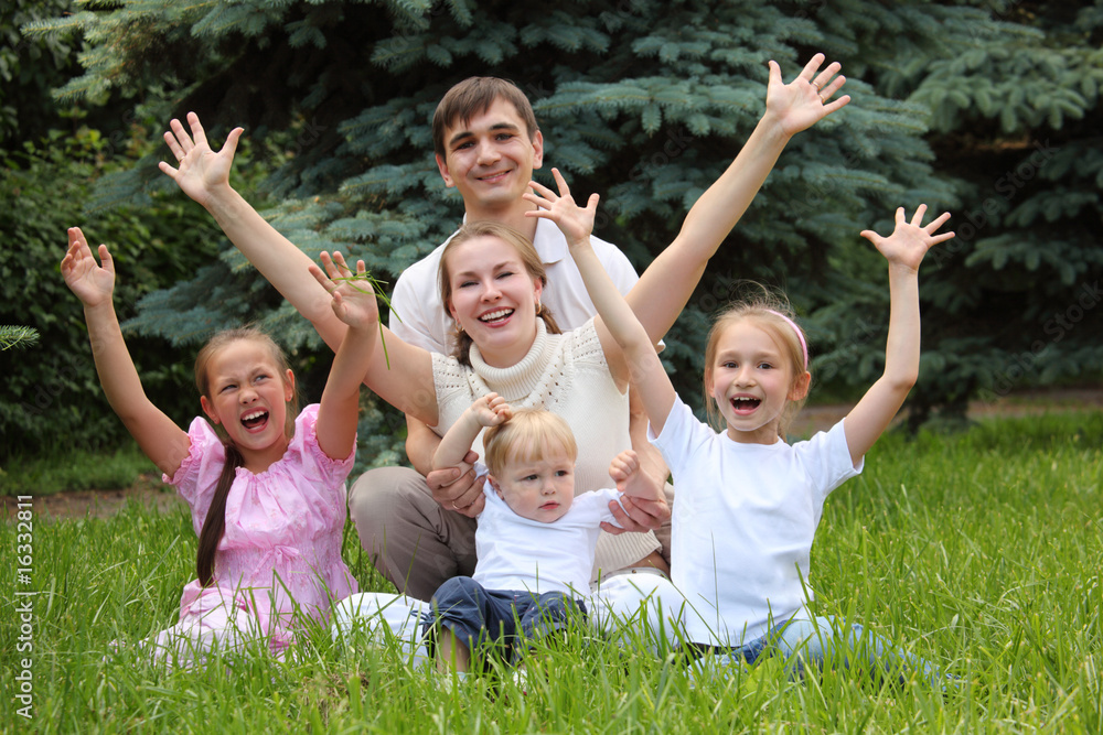 family of five rejoice outdoor in summer sit on grass