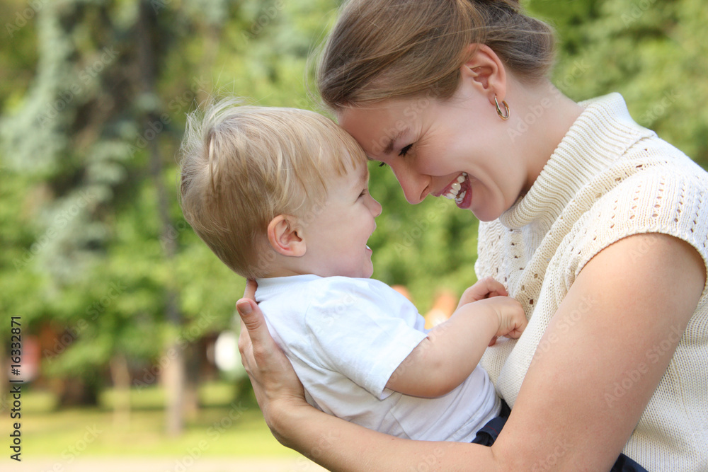 Mother hold baby on hands outdoor in summer and looks on each ot Mother hold baby on hands outdoor in summer and looks on each ot