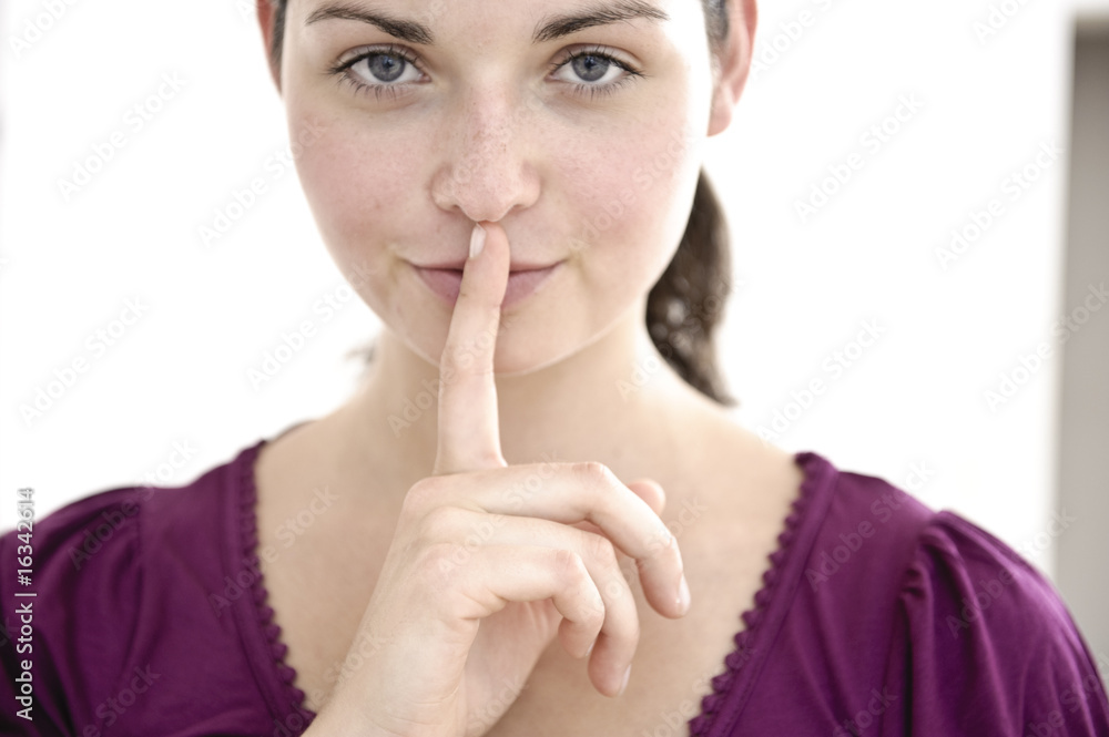 junge schöne frau legt geheimnisvoll finger auf lippen junge schöne frau legt geheimnisvoll finger auf lippen