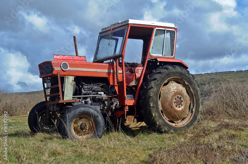 old Red tractor in rural farm field