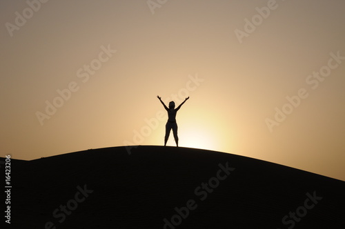 donna con le braccia al cielo su di una duna