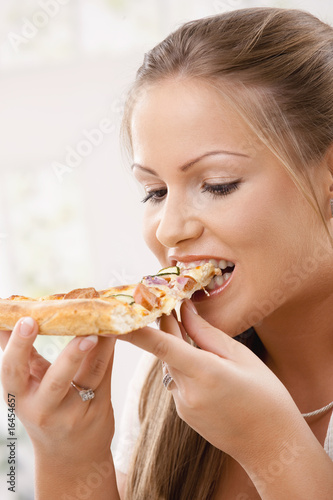 Young woman eating pizza slice