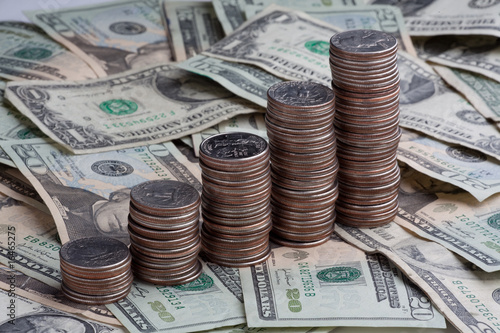 Increasing amounts of quarters on a field of bills