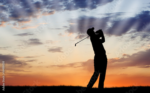 Golfer silhouetted against beautiful sunrise