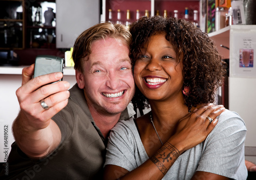 Mixed race couple in coffee house with taking picture cell phone photo