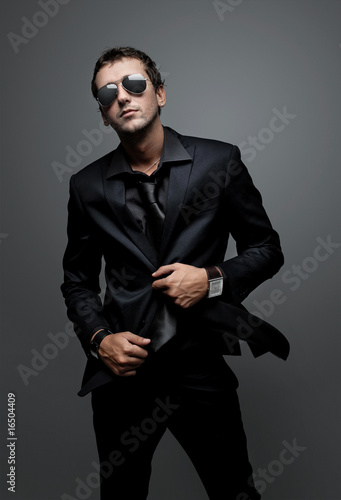 attractive young man wearing elegant black suit and sunglasses
