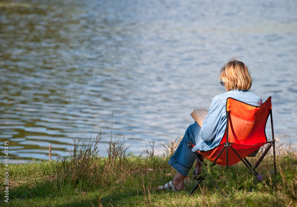 The woman reading the book on coast of lake The woman reading the book on coast of lake