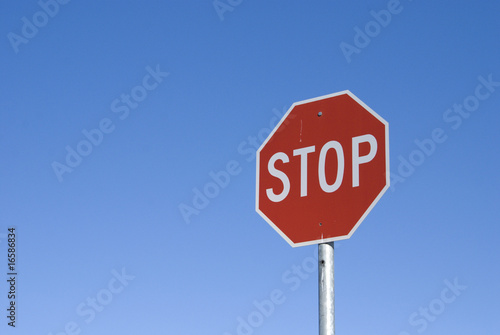 Real stop sign against clear blue sky.