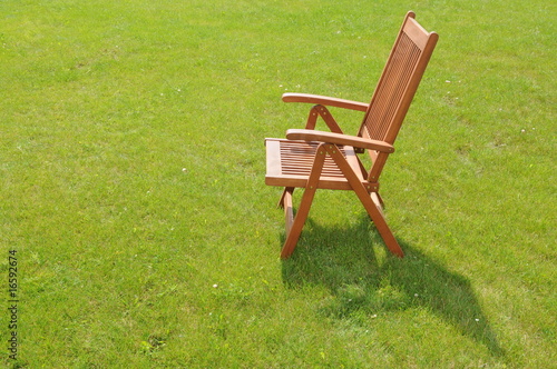 wooden chair in a green lawn © Fotique