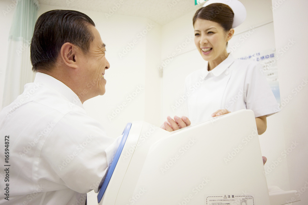 血圧を測る男性患者に話し掛ける看護師 血圧を測る男性患者に話し掛ける看護師