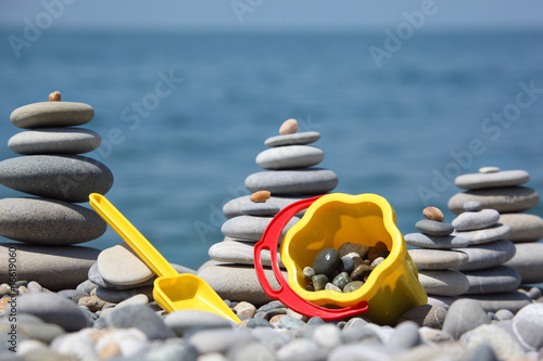 Yellow children's bucket with  scoop and stone stacks on seacoas photo
