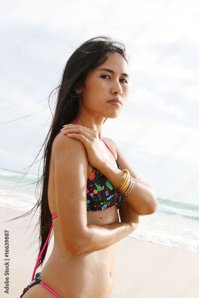 Beautiful Asian woman in a bright bikini at the beach. Beautiful Asian woman in a bright bikini at the beach.