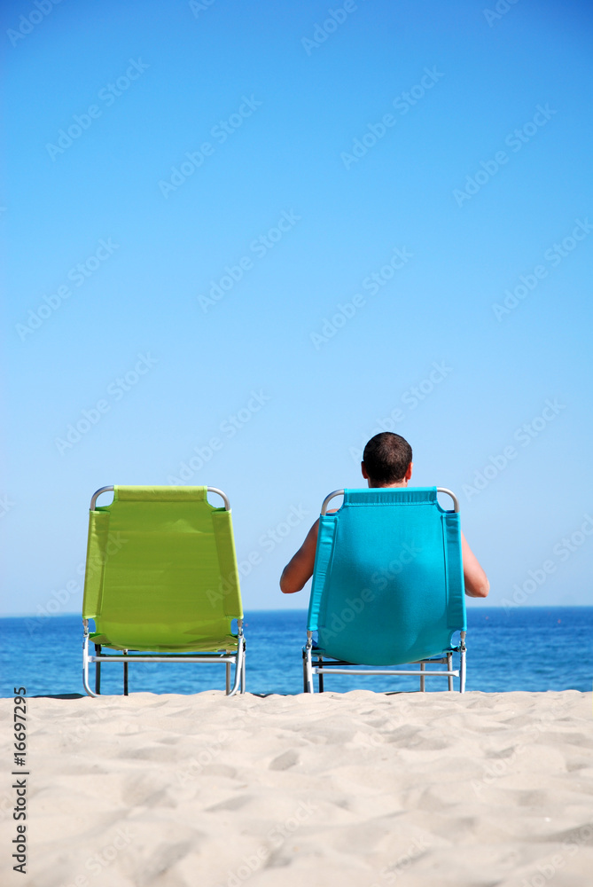 Man relaxing on sunbed at a beautiful beach Man relaxing on sunbed at a beautiful beach