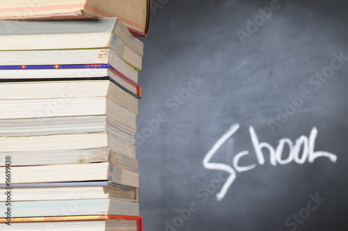 Stack of books in front of a chalkboard.
