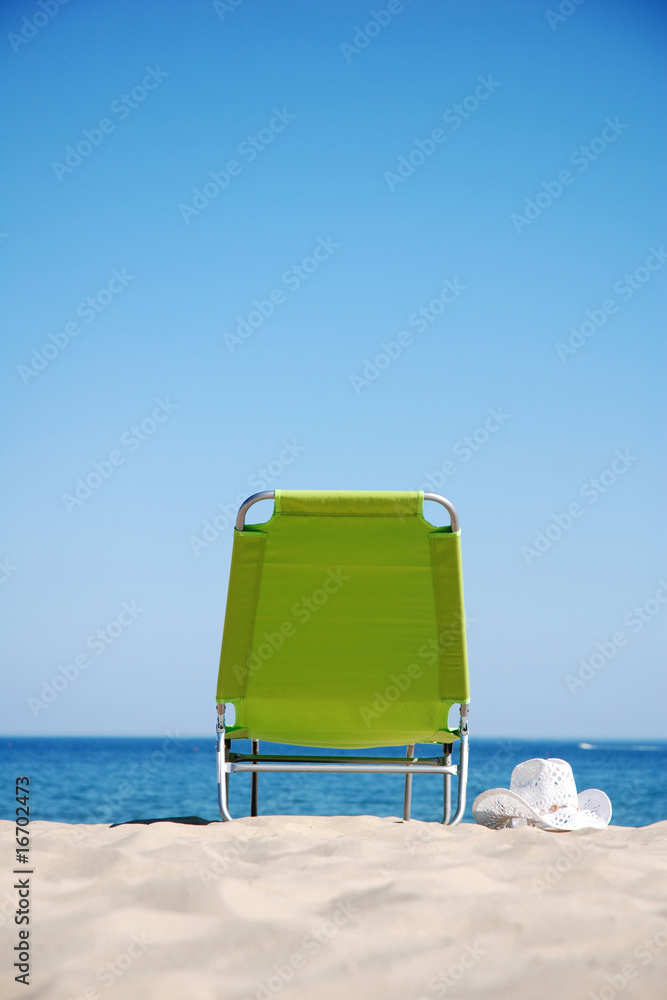 An empty deckchair and sunhat on a beautiful beach An empty deckchair and sunhat on a beautiful beach