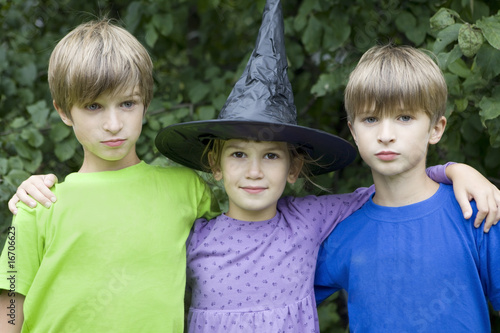 serious twins and girl in carnival hat playing in magician photo