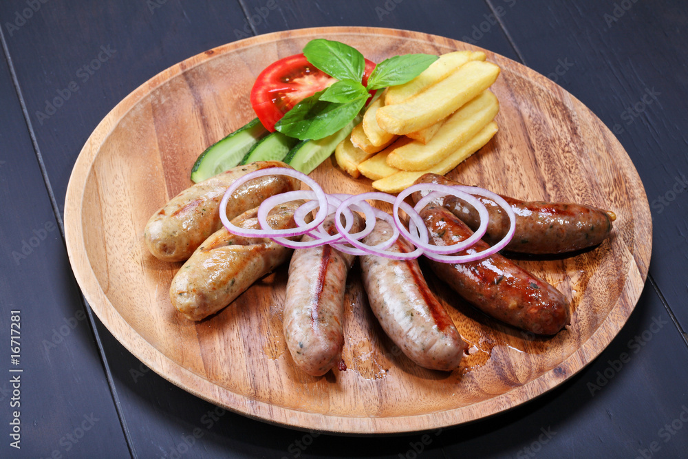 Assortment of grilled sausages on the wooden plate Assortment of grilled sausages on the wooden plate