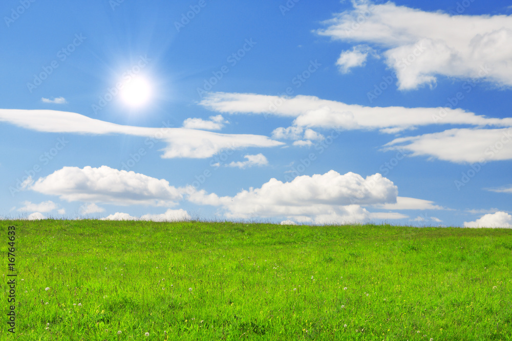 Obraz premium Green hill under blue cloudy sky whit sun