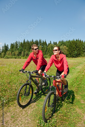 Sportive man and woman biking in a nature