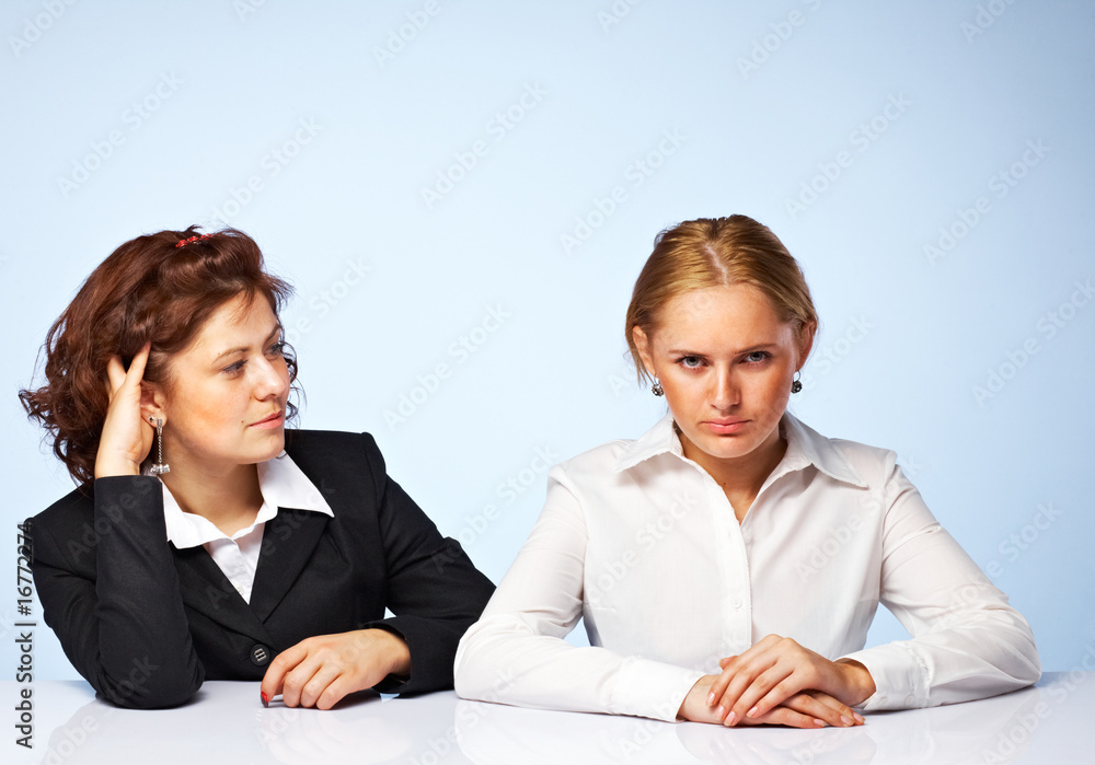 Two pretty confident business women against light background Two pretty confident business women against light background