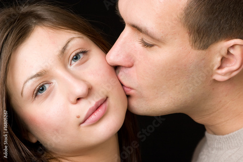 Man kisses young woman in cheek.