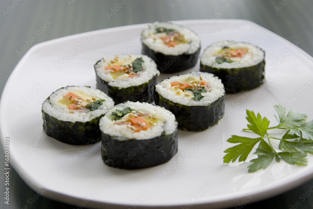 Six pieces of sushi and a parsley leaf.