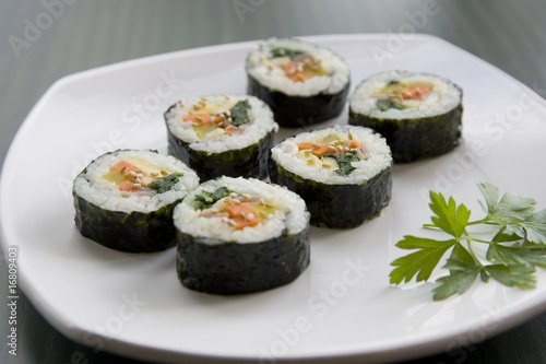 Six pieces of sushi and a parsley leaf.