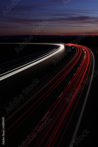 Cars in a rush moving fast on a highway (speedway) at dusk