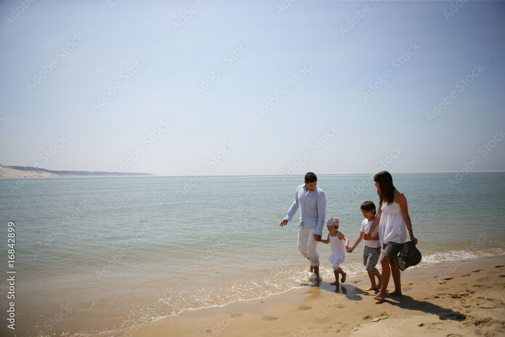 Homme et femme marchant au bord de la mer avec des enfants