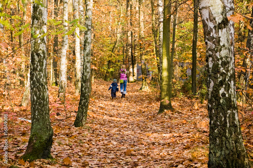 Mother and son walking in autumn forest