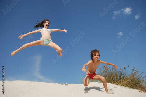 enfants sautant dans des dunes de sable blanc