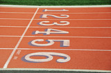 Lanes of a red race track with numbers and green football field
