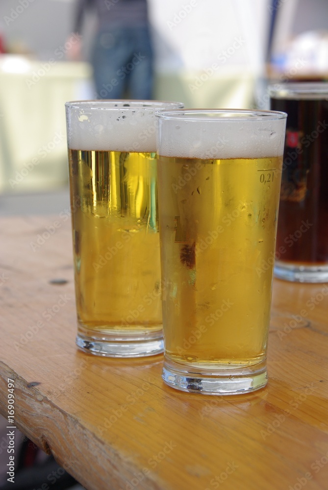 Two beers on a wooden bench in a biergarten Two beers on a wooden bench in a biergarten