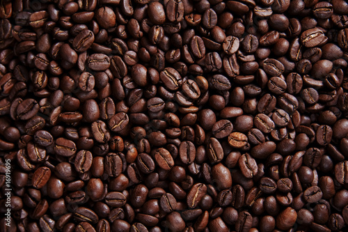 Draufsicht auf eine Menge an dunklem glänzendem Kaffee, geröstete Kaffeebohnen Hintergrundmuster Querformat