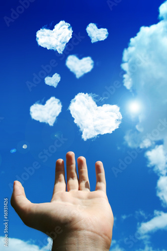 hand above lot of clouds of heart on the sky