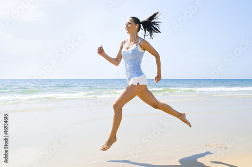 Junge sportliche Frau rennt am Strand photo