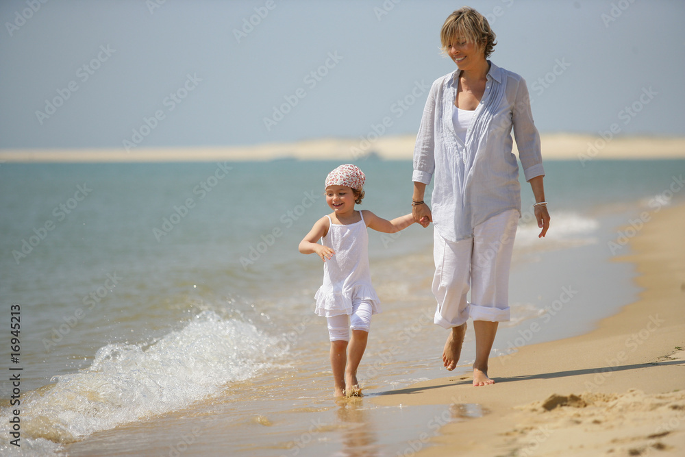 Femme se promenant au bord de la mer avec une petite fille