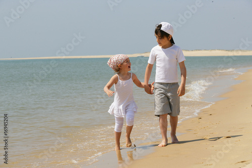 enfants marchant au bord de la mer en se tenant la main photo