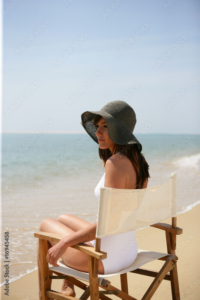 Portrait d'une femme assise sur une chaise au bord de la mer