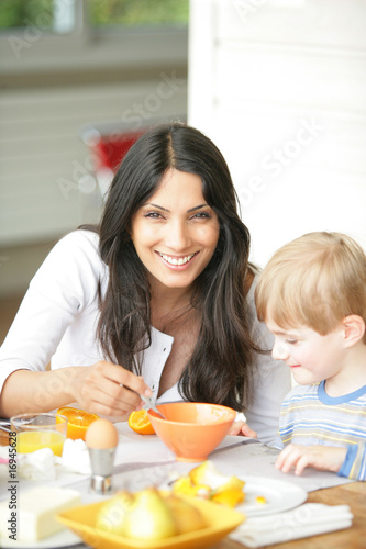 femme souriante près d'un petit garçon lui donnant à manger