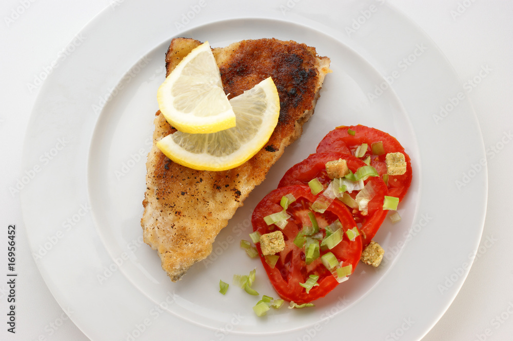 crumbed carp fillet on organic tomato on a plate crumbed carp fillet on organic tomato on a plate