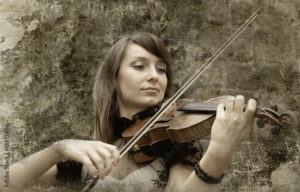 Beautiful female violinist playing violin on the grunge backgrou